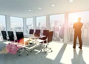Man standing in an office looking out of the window 